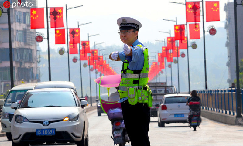 2019年9月30日,四川达州渠县公安交警在国旗下的路面指挥交通.